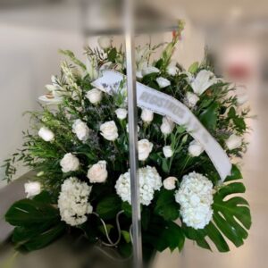 Centro de flores funerarias en abanico con rosas blancas y otras flores, todas blancas.