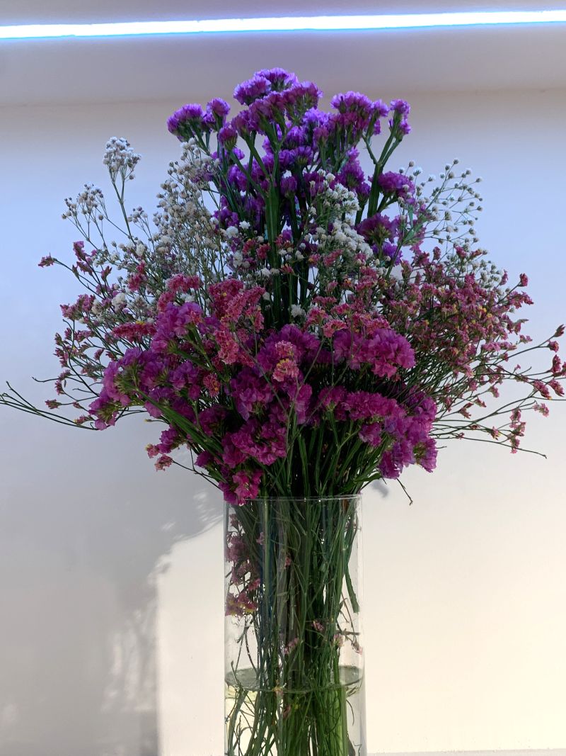 Decoración floral para locales comerciales en Málaga: ramo de flores secas preservadas, lilas y vioetas, decorando rincón de local comercial con iluminación especial.