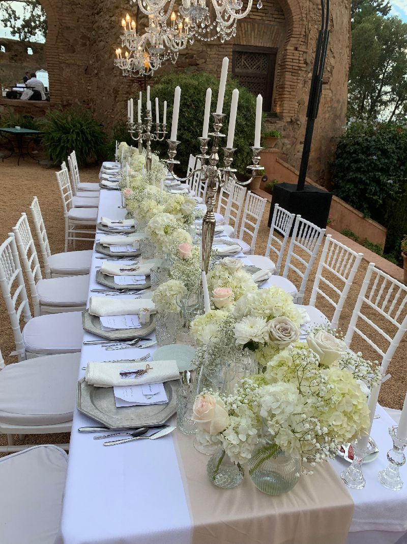 Mesa para evento en Málaga, decorada elegantemente con flores diversas en tonos blancos y beiges.
